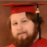 Man in graduation gown with a beard, close-up portrait