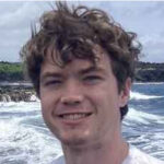 Guy with waves in background smiling for camera