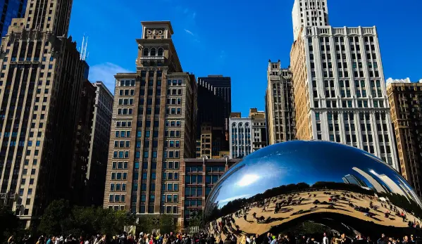A modern metal structure stands tall, mirrored beautifully in the water below.