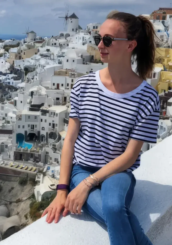 Girl sitting on wall with buildings in background